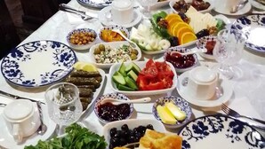 A table set with various dishes, including bread, vegetables, and a coffee pot.
