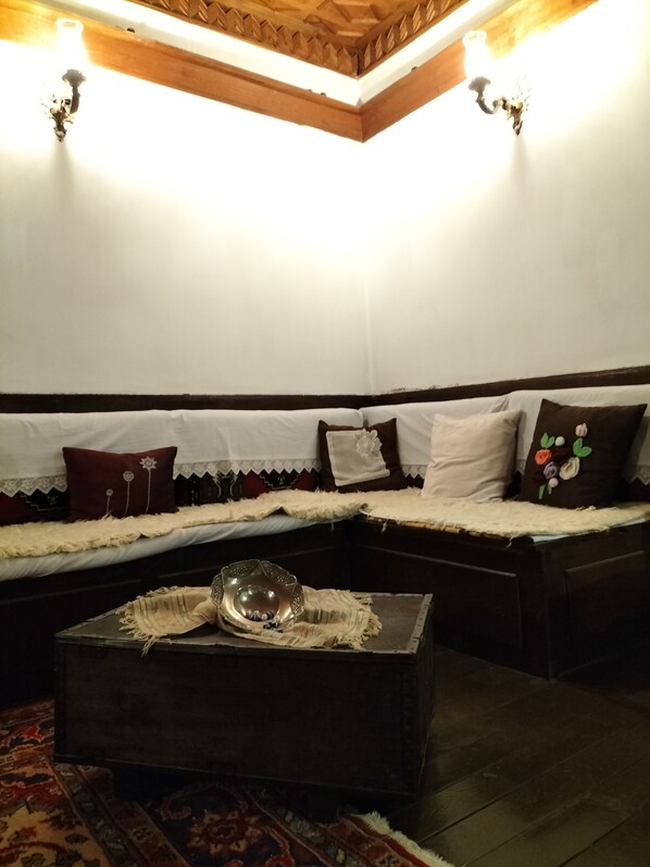 A cozy sitting area with a sofa, a decorative bowl on a chest, and a patterned rug. - Turgut Reis Konak Otel (Safranbolu)