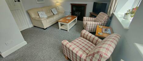 A living room with a beige sofa, a plaid sofa, a wooden coffee table, and a fireplace.