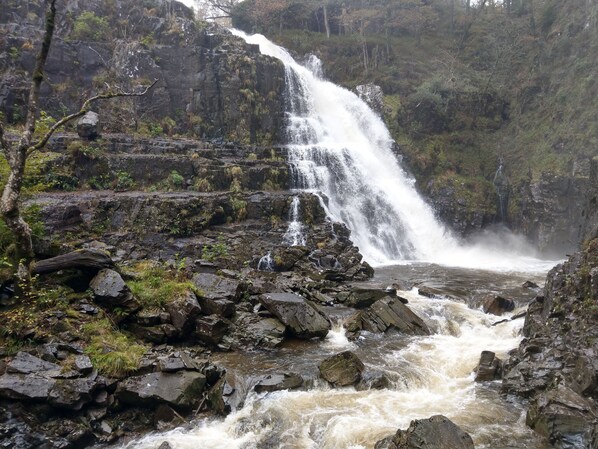 A waterfall cascading over rocky terrain with lush greenery around. - Pant Glas Barn (Llanbrynmair)