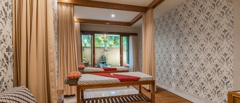 A room with a wooden bed, a wooden bench, and a view of a garden through a glass door.