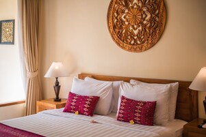Una cama bien hecha con almohadas de diseño blanco y rosa, un cabecero de madera y un adorno de pared decorativo.