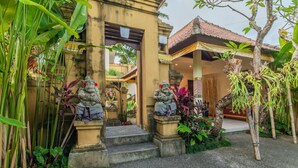 A traditional building with a tiled roof, stone statues, and a staircase leading to the entrance.