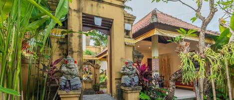 A traditional building with a tiled roof, stone statues, and a staircase leading to the entrance.