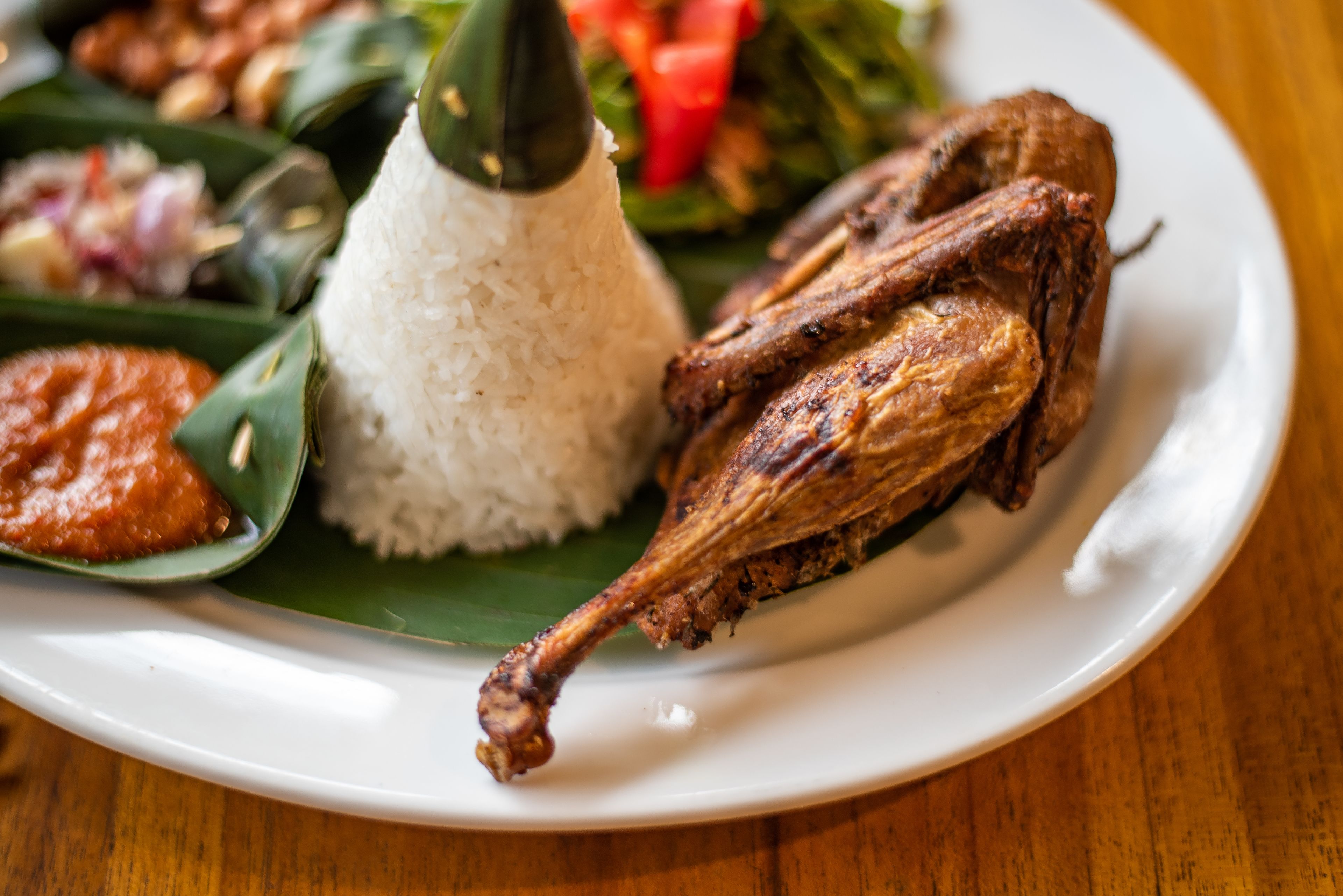 A plate with white rice, a roasted chicken leg, and a side of vegetables.