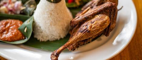 A plate with white rice, a roasted chicken leg, and a side of vegetables.