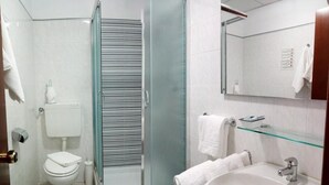 A modern bathroom with a glass shower enclosure, a white toilet, a sink with a glass shelf, and a mirror. - Hotel San Nazario (Varazze)