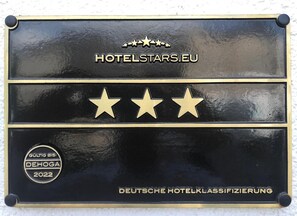 Una placa negra con letras doradas y estrellas, que indica la categoría de un hotel.