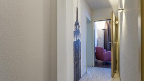 Un pasillo con un mural de la construcción del Empire State, una silla roja y una puerta que da a una habitación.