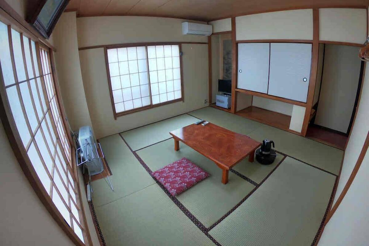 A traditional Japanese room with tatami flooring, a low wooden table, a television, and sliding doors.