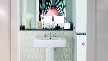 Un baño con un lavamanos blanco, un espejo y suelo de baldosas.