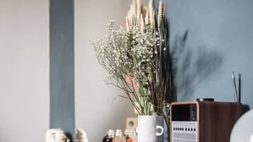 Un interior moderno con una consola de madera oscura contra una pared azul, sosteniendo un jarrón con flores secas, un pequeño jarrón blanco y una radio antigua.