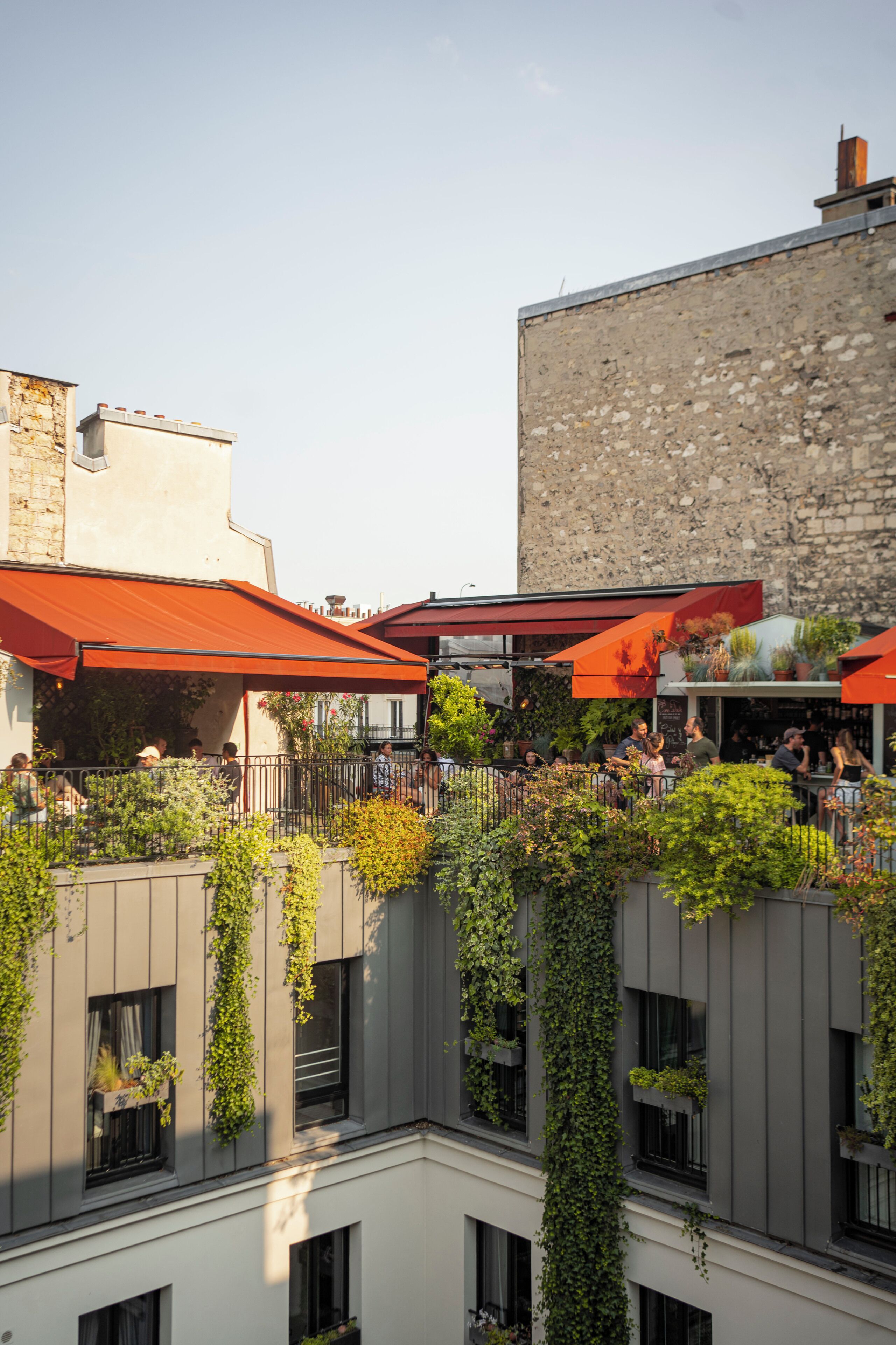 Une cour avec un bâtiment au toit rouge, un mur de pierre et de la verdure.