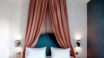 Une chambre à coucher avec un lit à baldaquin, deux tables de chevet avec des lampes et un mur d’accent de couleur foncée.