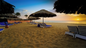 A beach with sun loungers and thatched umbrellas, a clear sky, and a sunset. - Kefi Palmera Beach Resort El Sokhna - Family Only (Ataqah)