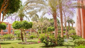 A well-maintained garden with palm trees, flowering bushes, and a neatly trimmed lawn. - Kefi Palmera Beach Resort El Sokhna - Family Only (Ataqah)