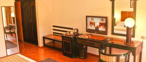 A hotel room with a bed, a desk with a chair, a television, and a mirror.