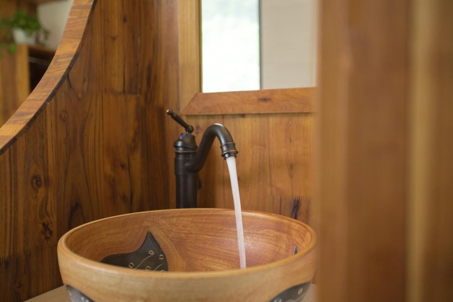 Een houten wasbak met een kraan en stromend water.