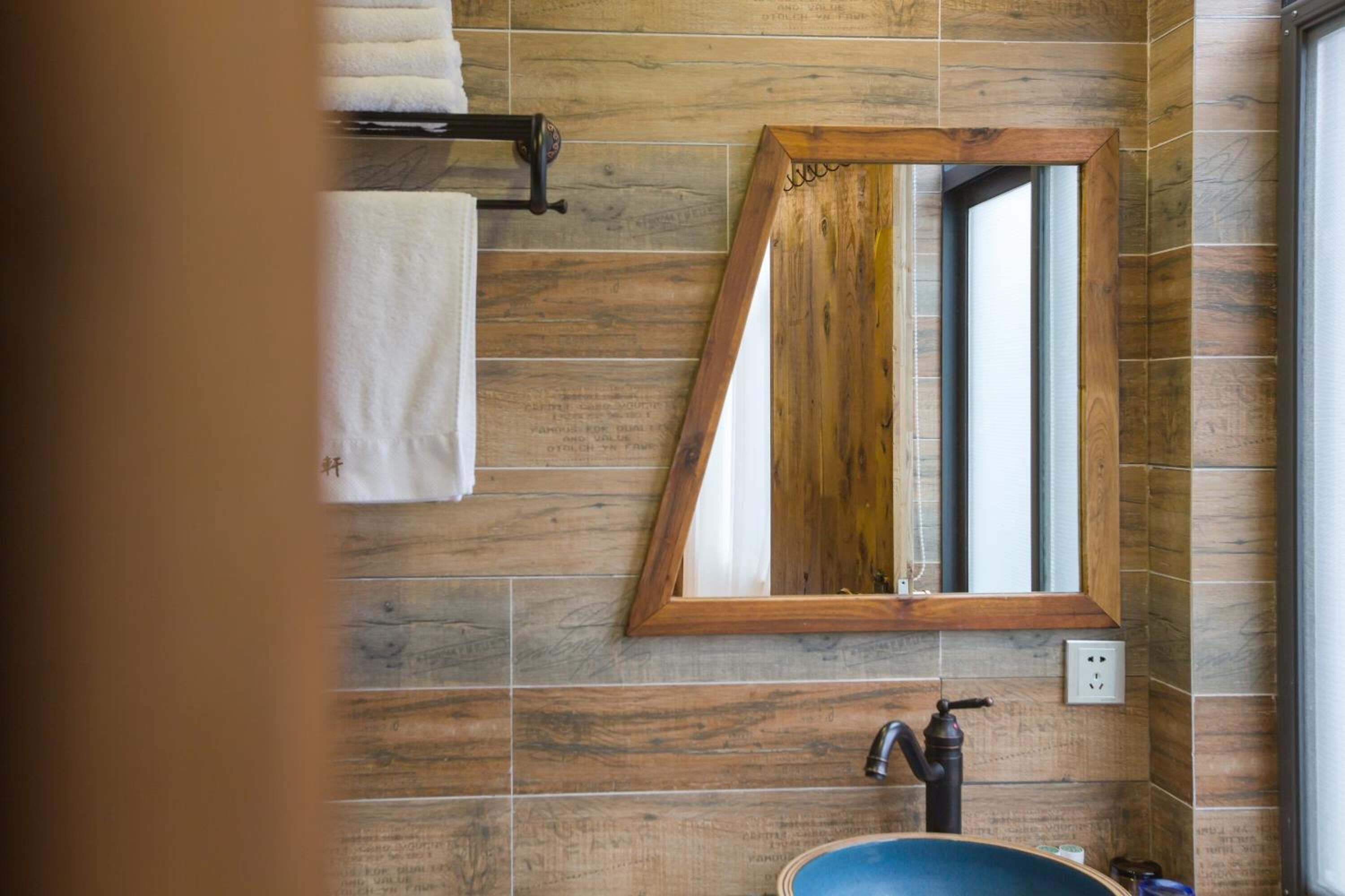 Een badkamer met houten tegels, een wastafel, een spiegel en een handdoekhouder.