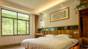 Un dormitorio moderno con una cama grande, cabecera de madera y vistas a zonas verdes a través de un ventanal.