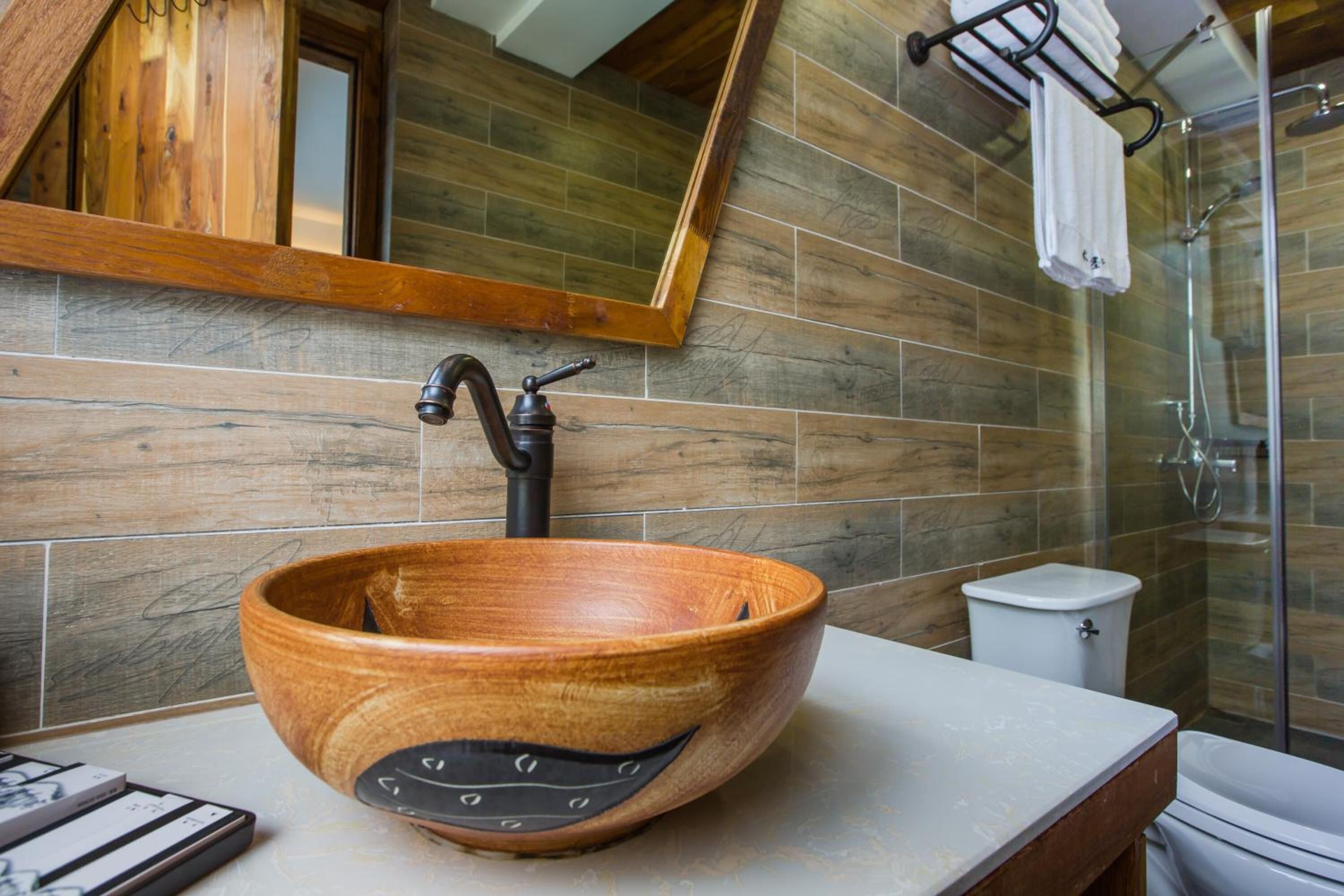 Un lavabo de madera en un baño moderno con techo inclinado, un inodoro y una zona de ducha.