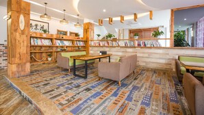 Una biblioteca acogedora con estanterías de madera, asientos cómodos y una alfombra estampada.