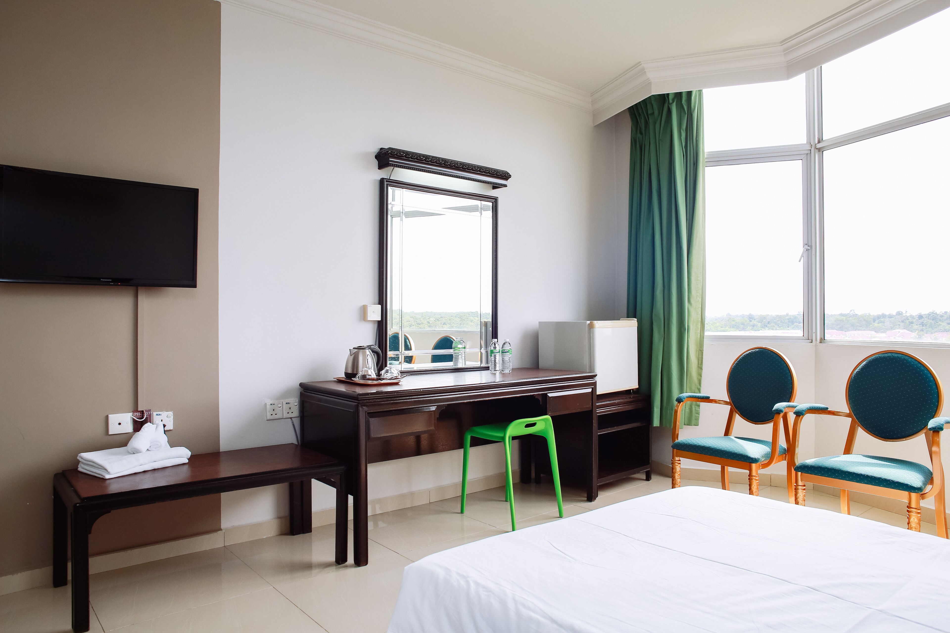 Habitación de hotel con cama, escritorio, silla, televisor y ventana con vistas.