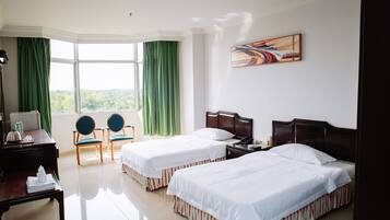 Habitación de hotel con dos camas, un escritorio, sillas, un cuadro y vistas a zonas verdes.