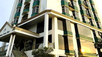 A tall hotel with multiple balconies, a central staircase, and a sign reading "Hotel Green Park".