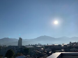 Un paisaje urbano con una torre destacada y montañas al fondo.
