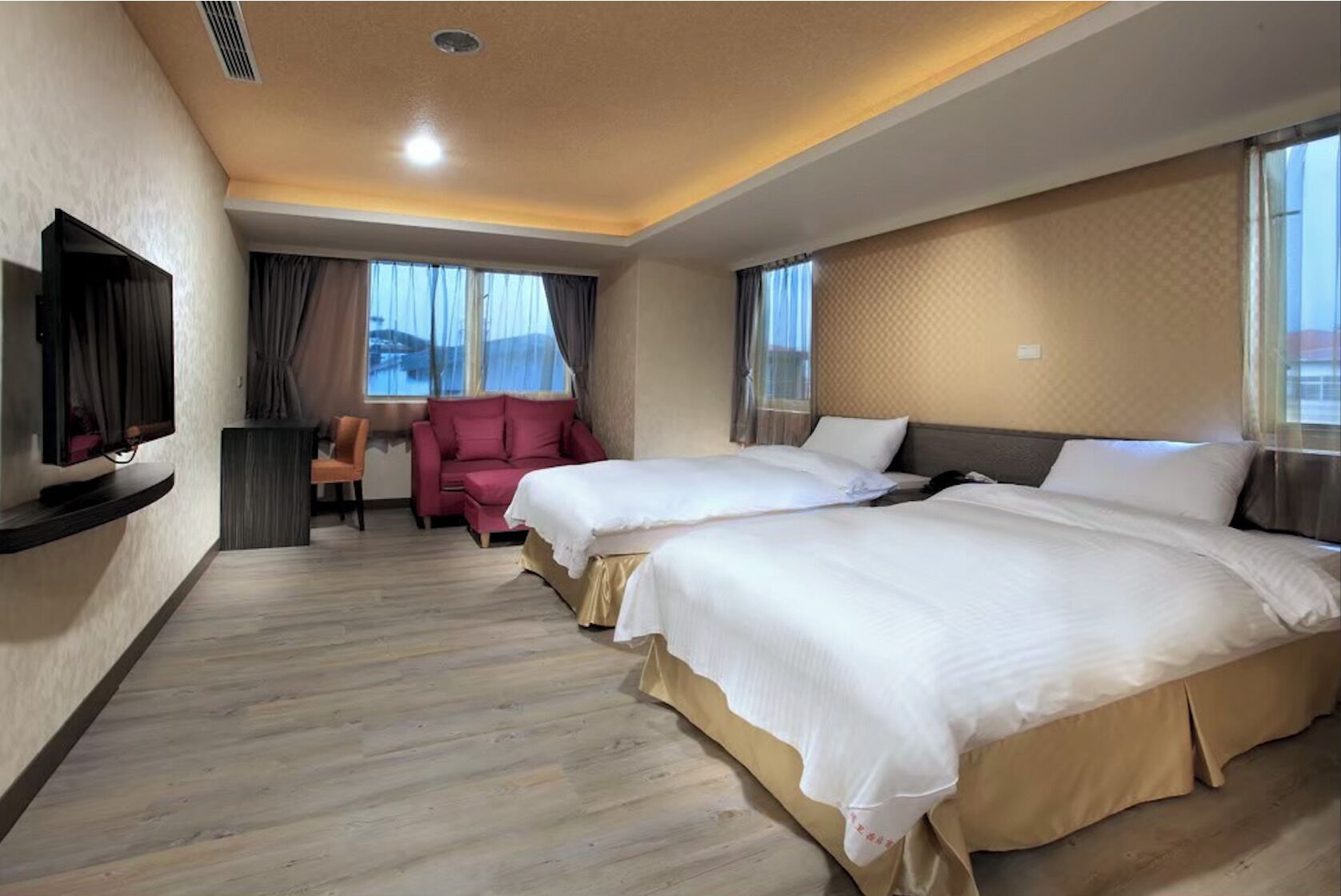 A hotel room with two beds, a TV, a desk, and a chair.
