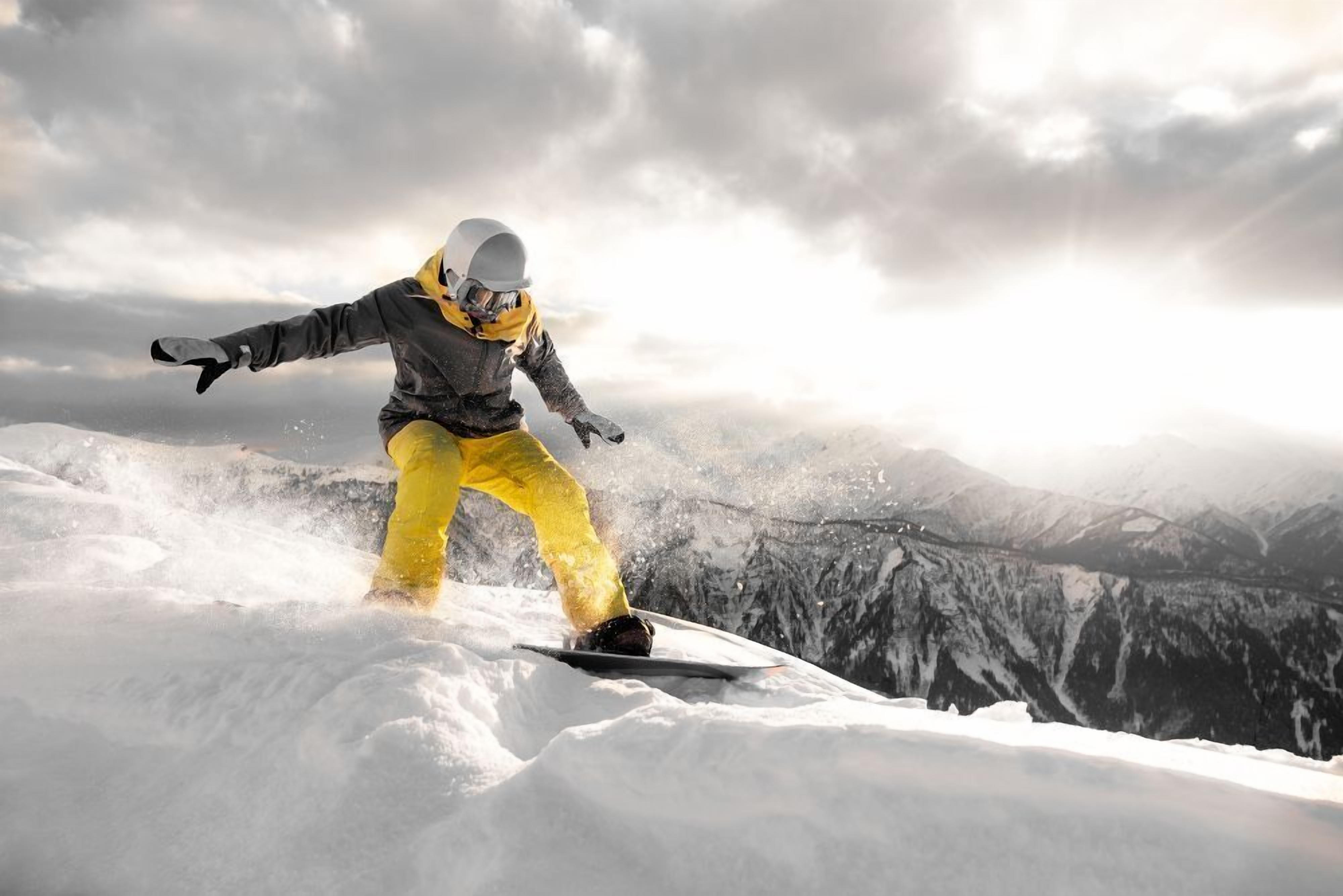 Ein Snowboardfahrer in verschneiter Landschaft, im Hintergrund Berge.