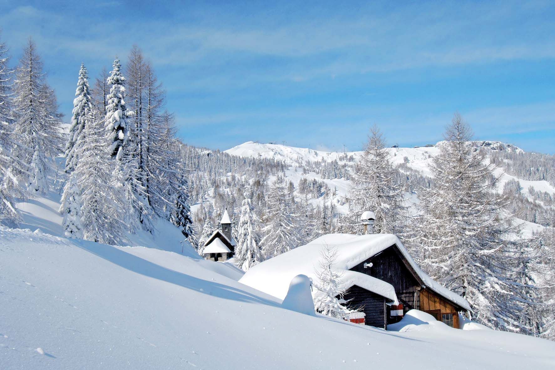 A snow-covered mountain landscape with a wooden cabin and a church.