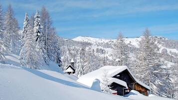 A snow-covered mountain landscape with a wooden cabin and a church.