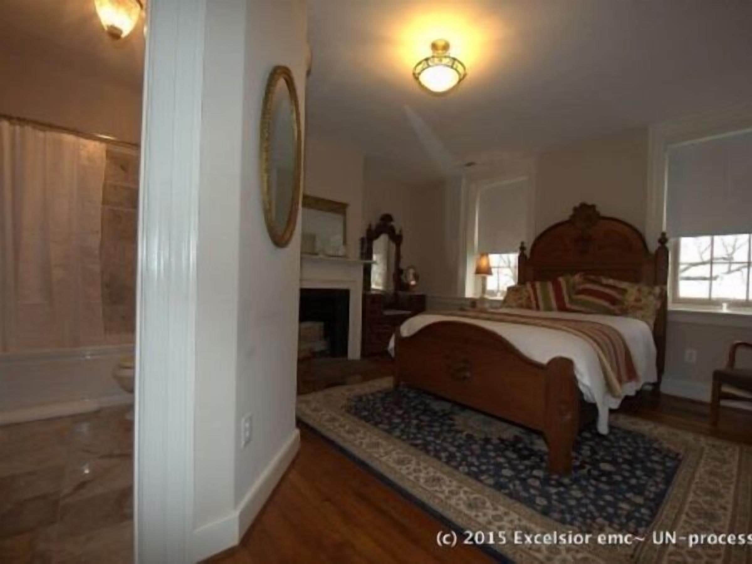 A bedroom with a wooden bed, a nightstand, a lamp, and a window.