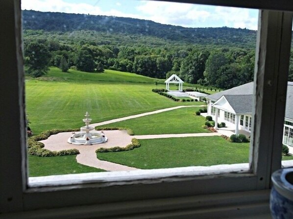 A view of a well-maintained lawn with a gazebo and a fountain, surrounded by a white building with large windows.