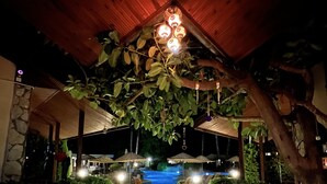 An outdoor patio area with a swimming pool, seating arrangements, and a wooden ceiling structure. - Grenadine Lodge (Ortaca)