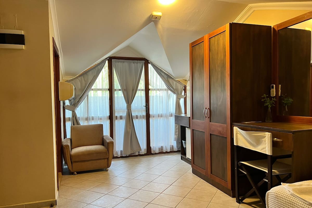 A bedroom with a bed, a chair, a desk, and a wardrobe.