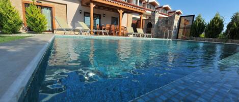 Une piscine avec des chaises longues et un espace patio couvert.