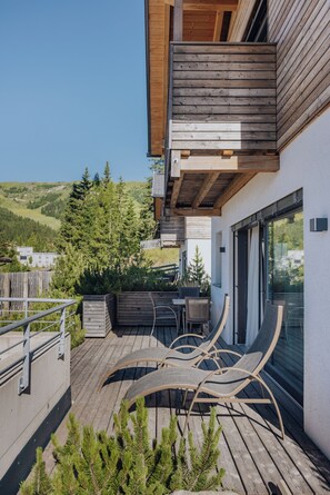 Eine moderne Außenterrasse mit Holzmöbeln und Blick auf die umliegende Landschaft.