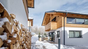 Ein modernes Gebäude mit Holzfassade, einem Balkon und verschneitem Gelände.
