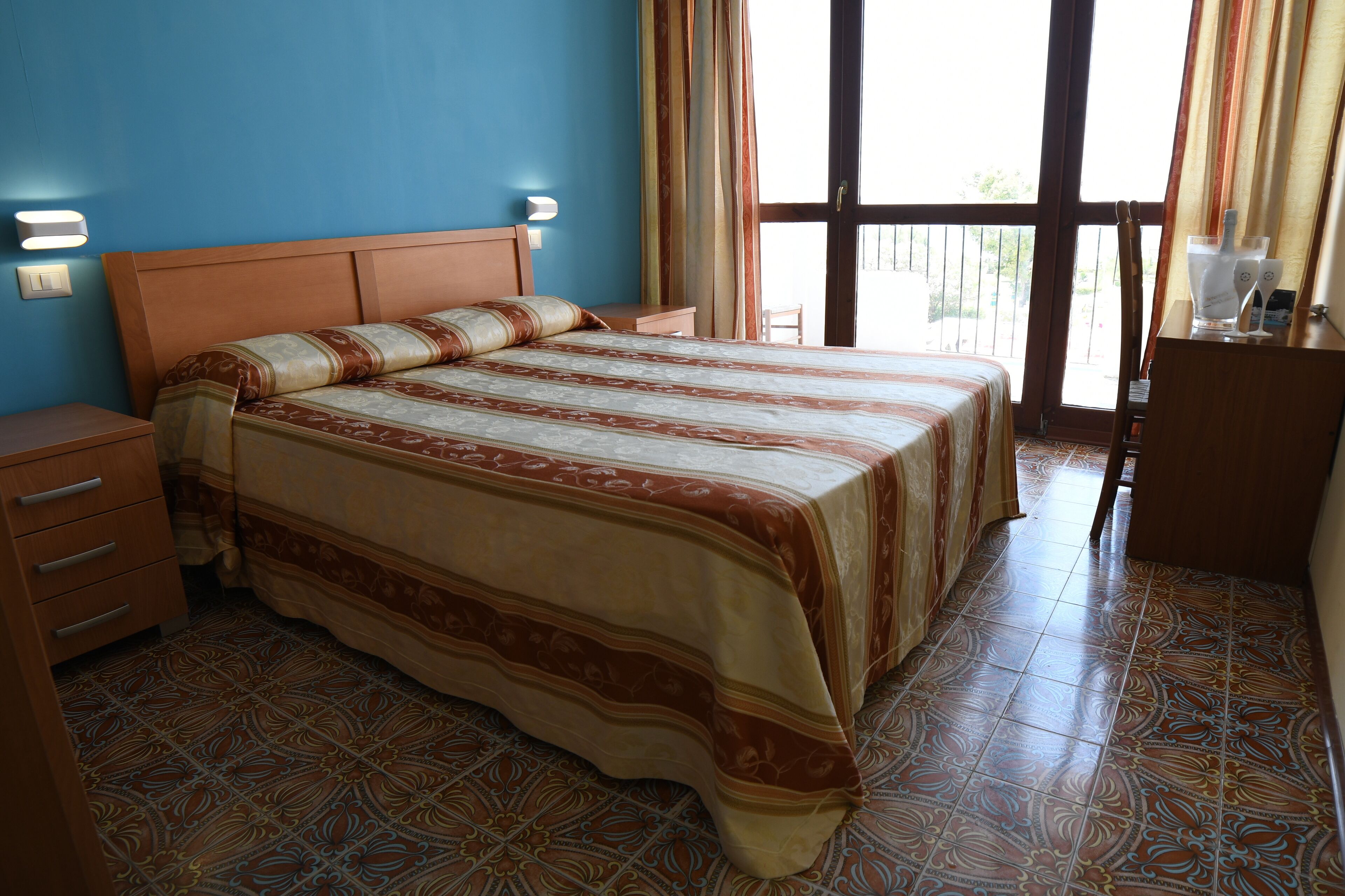 A bedroom with a large bed, a nightstand, a dresser, and a window with curtains.