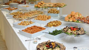 A buffet table with various food items, including salads, sandwiches, and pastries, arranged on white trays and plates.