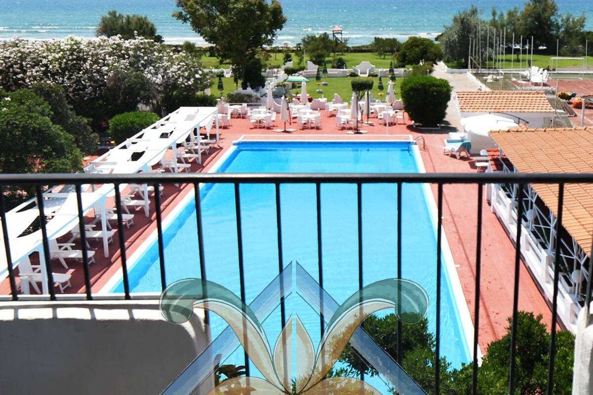 En pool med utsikt över havet, omgiven av solstolar och parasoller.