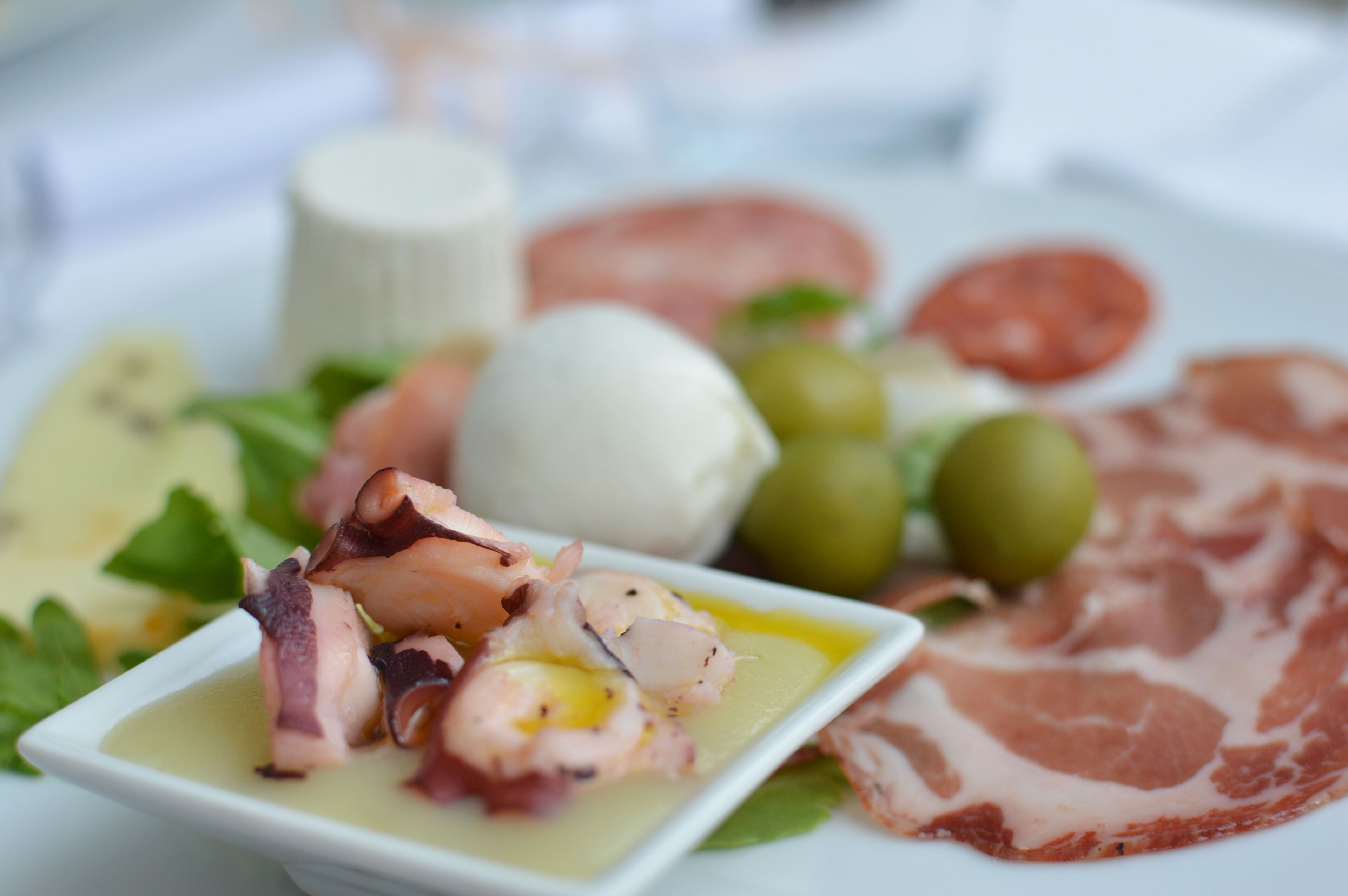 A plate of food including seafood, cheese, and cured meat.