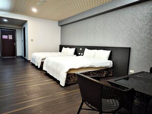 A hotel room with two beds, a dining table, and chairs.