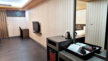 A hotel room with a television, a coffee maker, a mirror, and a small desk.