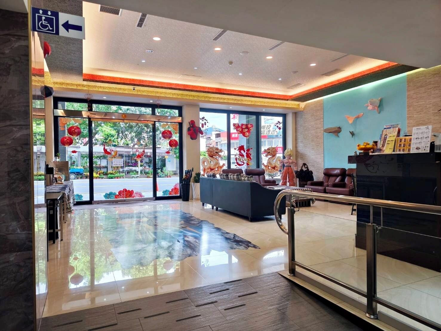 Um hall de hotel com balcão de recepção, área de estar e grandes portas de vidro que dão para o exterior.