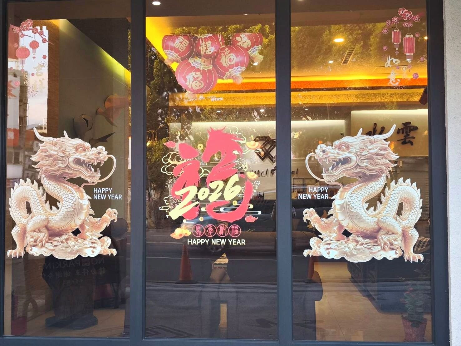 A storefront with festive decorations for the New Year, including two dragon figures and a large red lantern.