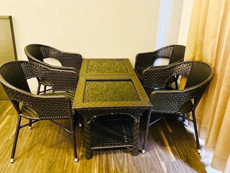 A dining area with a table and four chairs, a patterned tablecloth, and a wooden floor.